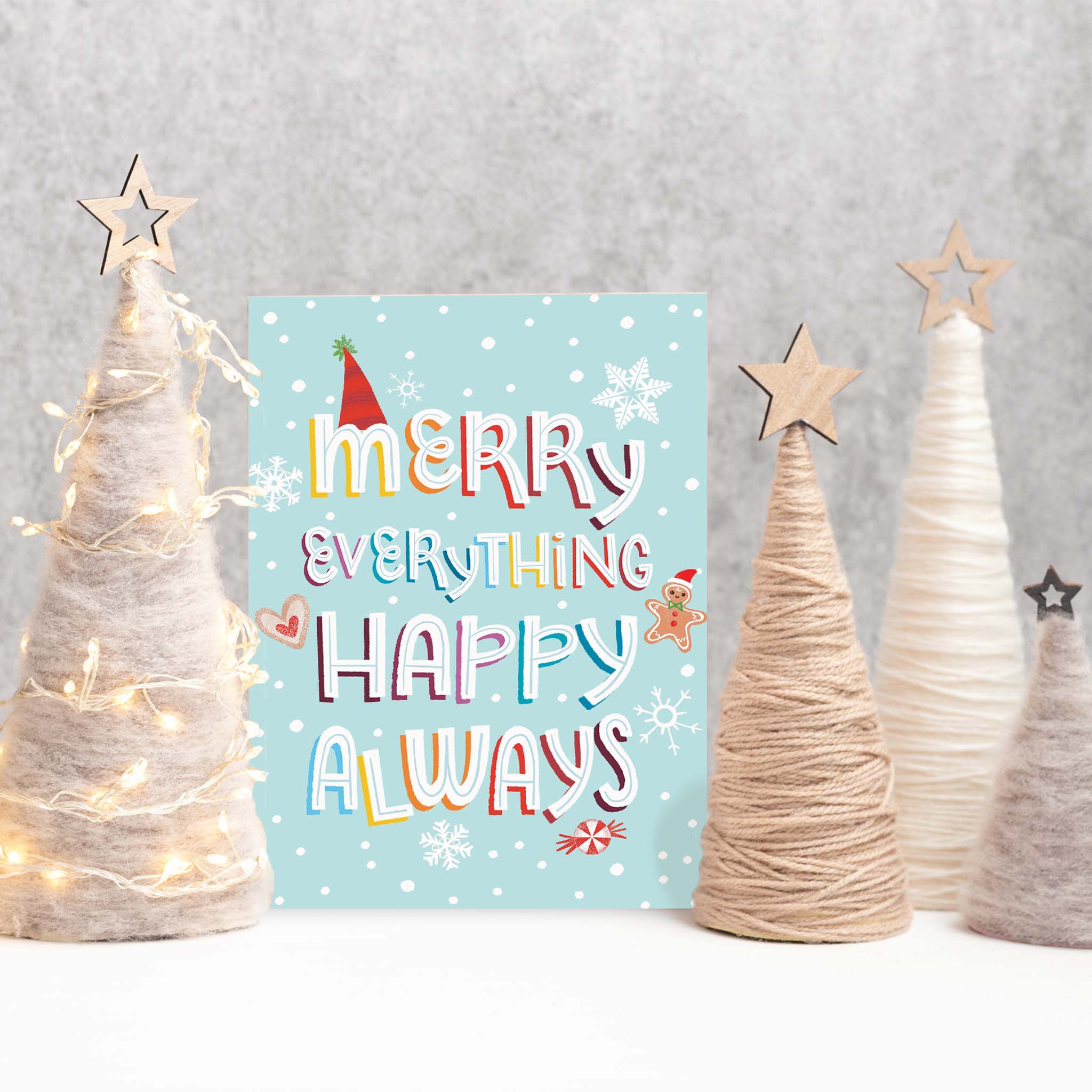 Christmas card with colorful text surrounded by decorative trees on a gray background