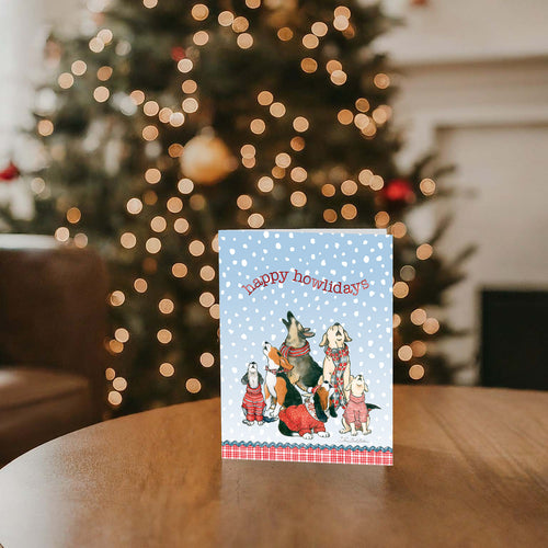Canine Choir - 26 Special Finish Boxed Christmas Cards on a table, with a Christmas tree in the background
