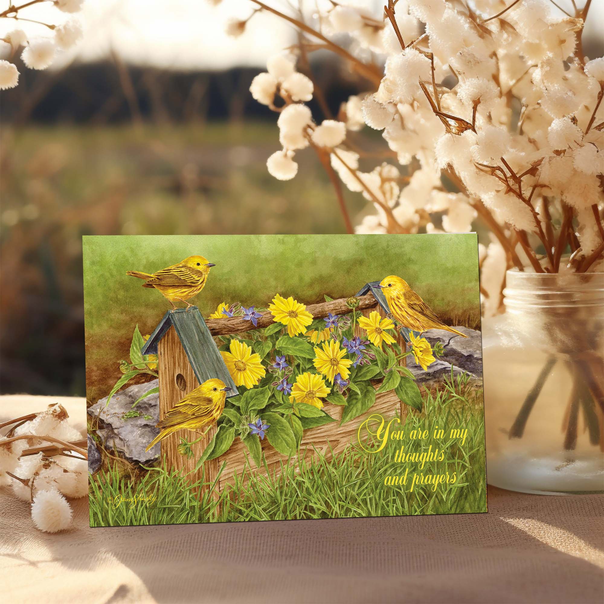 Greeting card with yellow birds and flowers on a wooden post, surrounded by cotton plants.