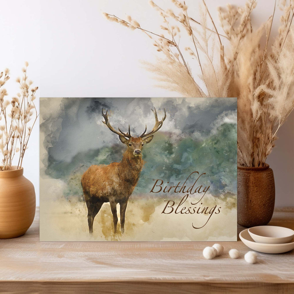 Greeting card with a deer illustration and 'Birthday Blessings' text, placed on a wooden surface with decorative elements.