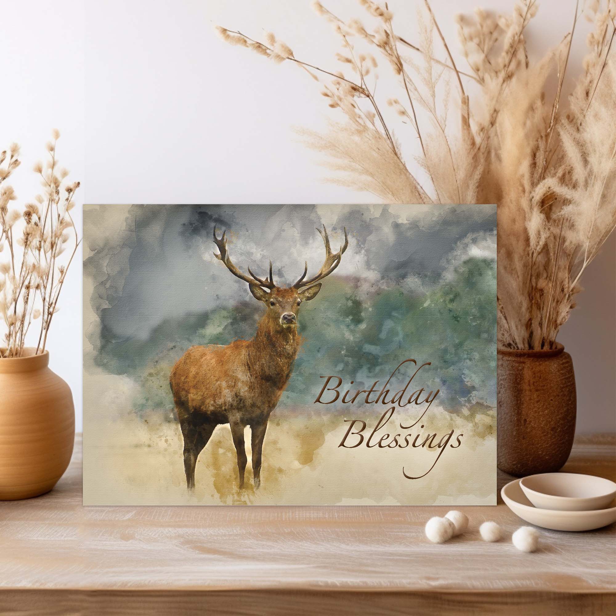 Greeting card with a deer illustration and 'Birthday Blessings' text, placed on a wooden surface with decorative elements.