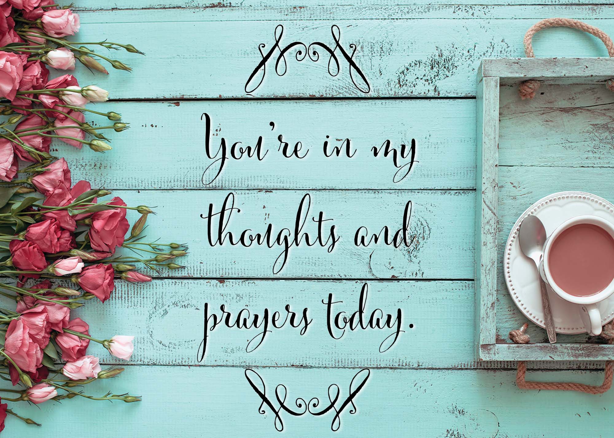 Teal wooden board with floral decoration and a cup of tea, featuring the text 'You're in my thoughts and prayers today'.