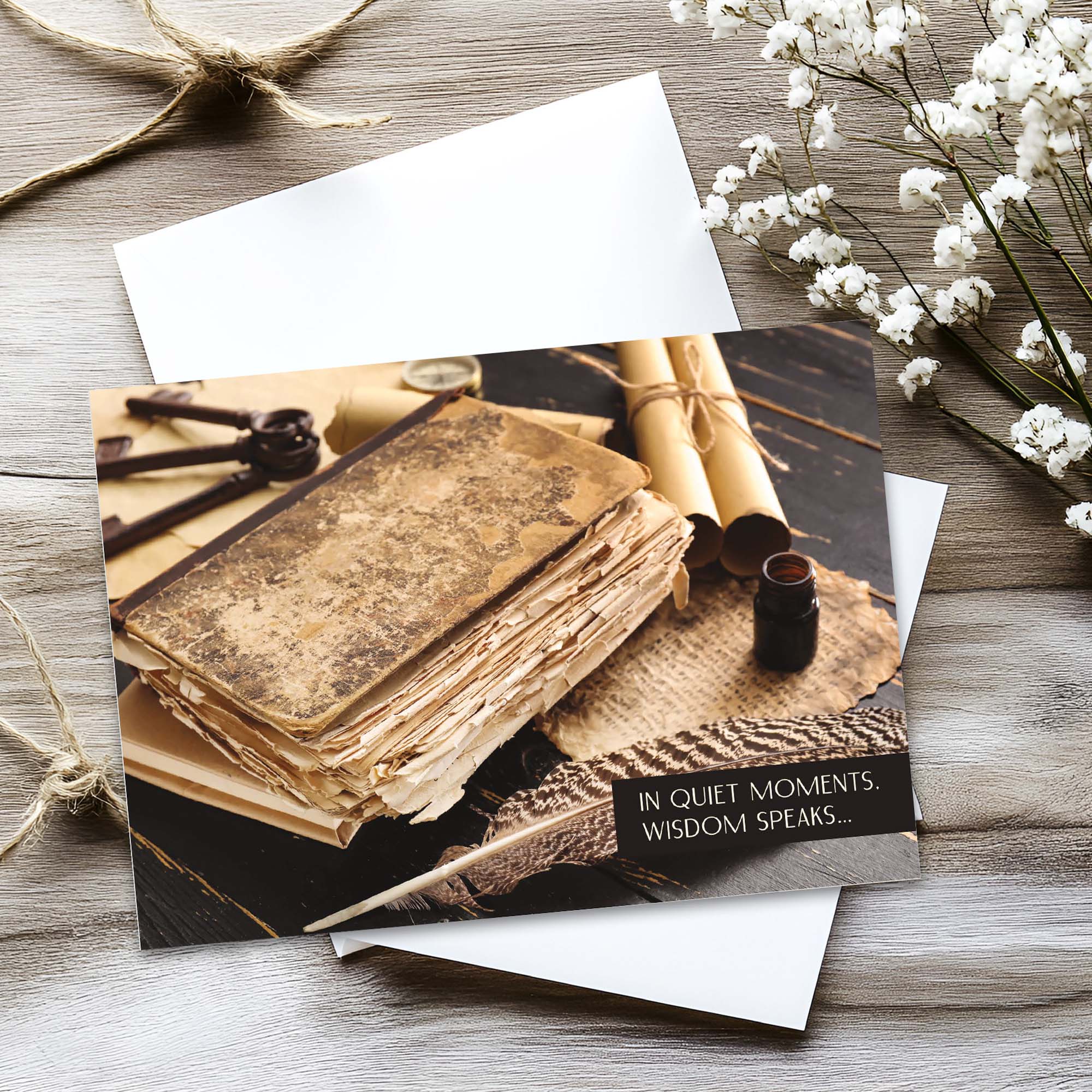 Greeting card with vintage books and a bottle on a wooden surface with flowers.