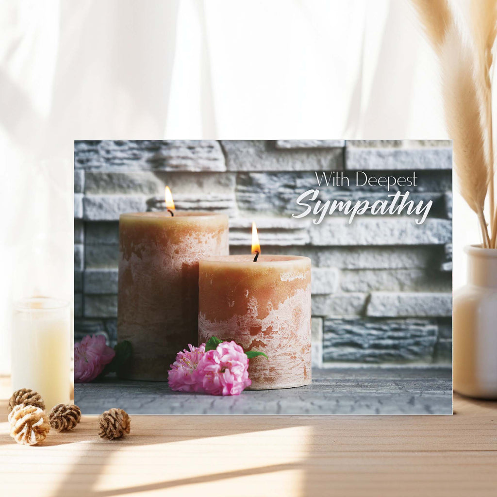 Sympathy card with two candles and flowers on a wooden surface