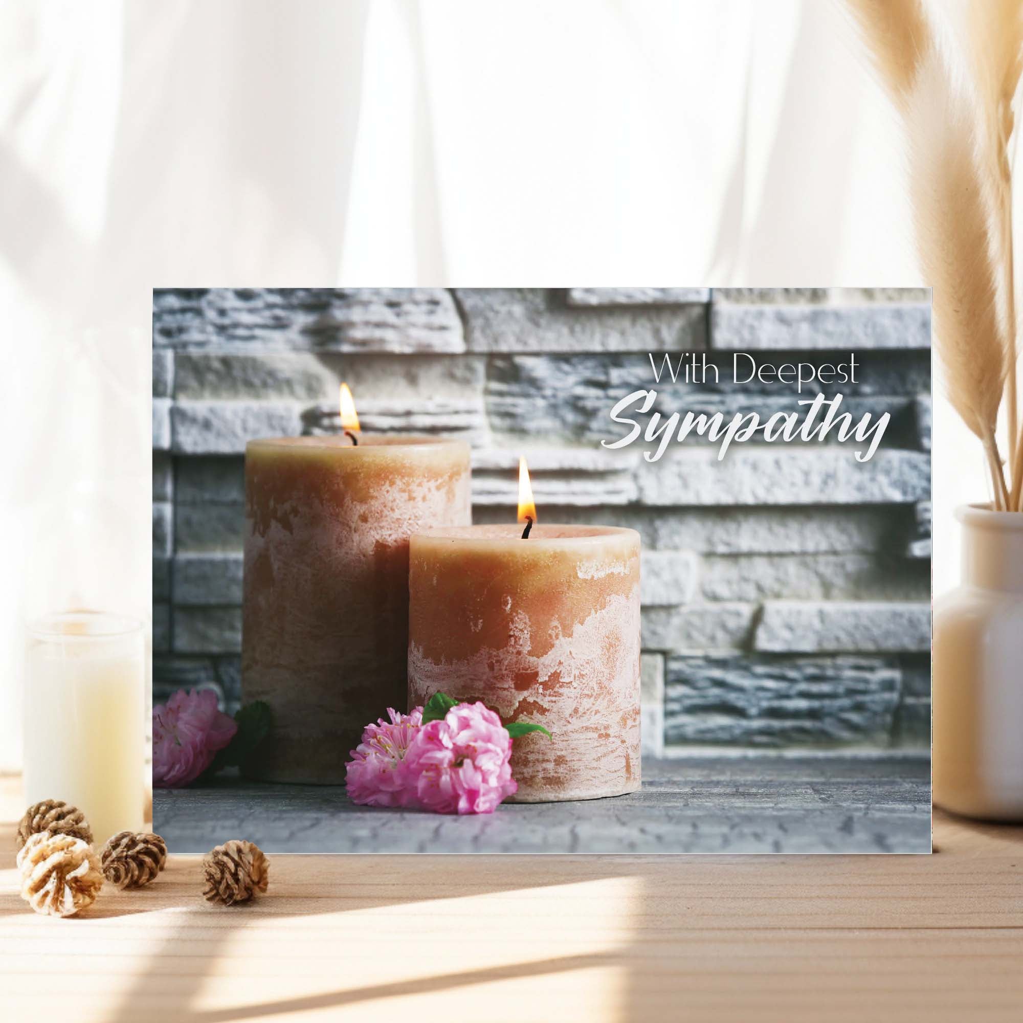 Sympathy card with two candles and flowers on a wooden surface