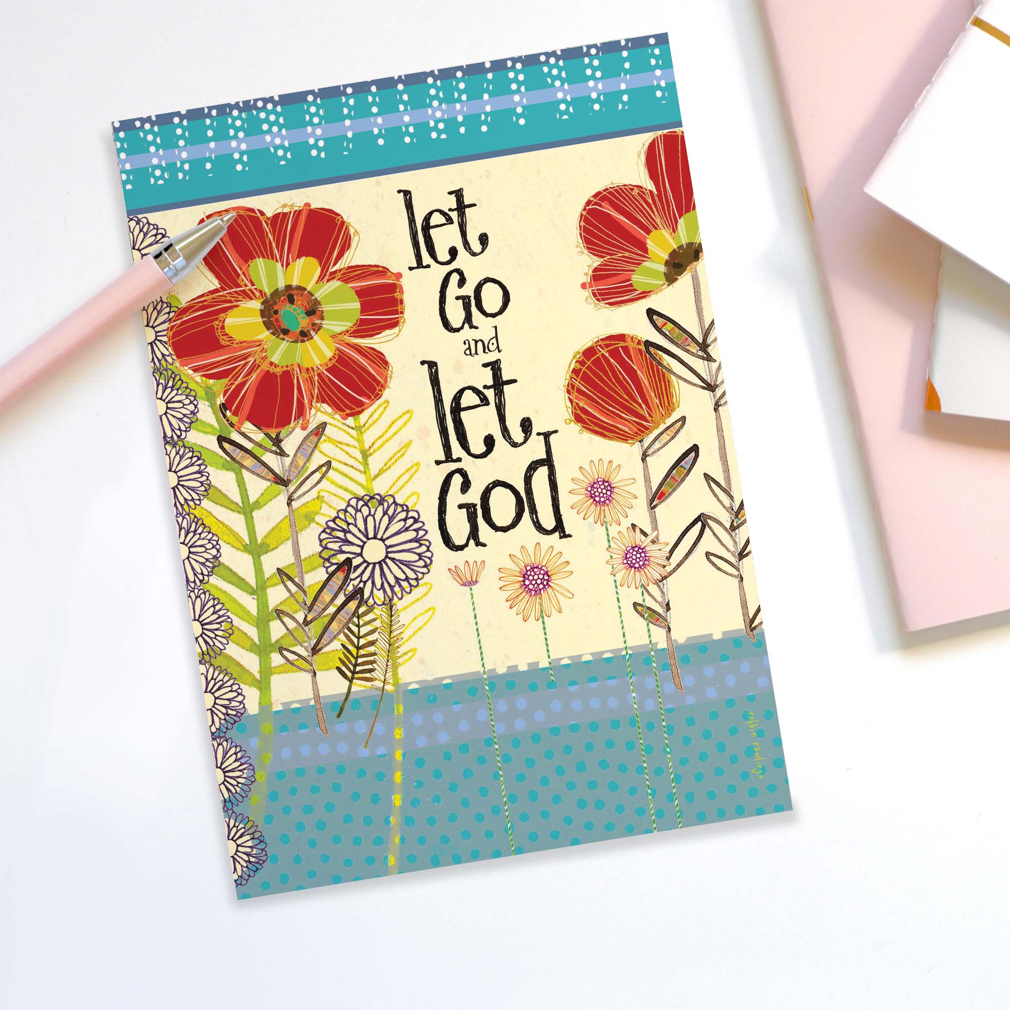 Notebook with floral design and 'let go and let God' text on a white background