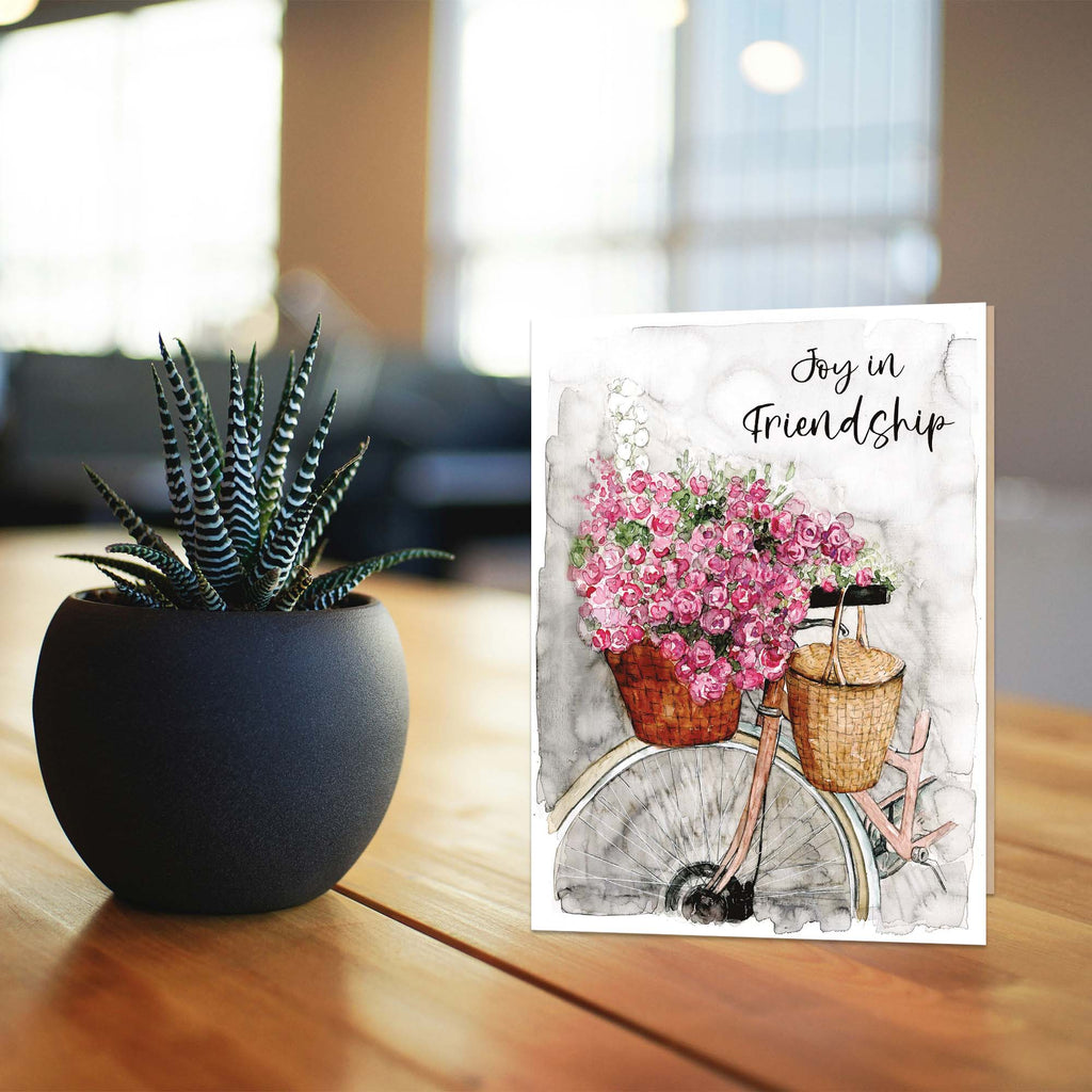 Potted plant next to a greeting card with flowers on a wooden surface