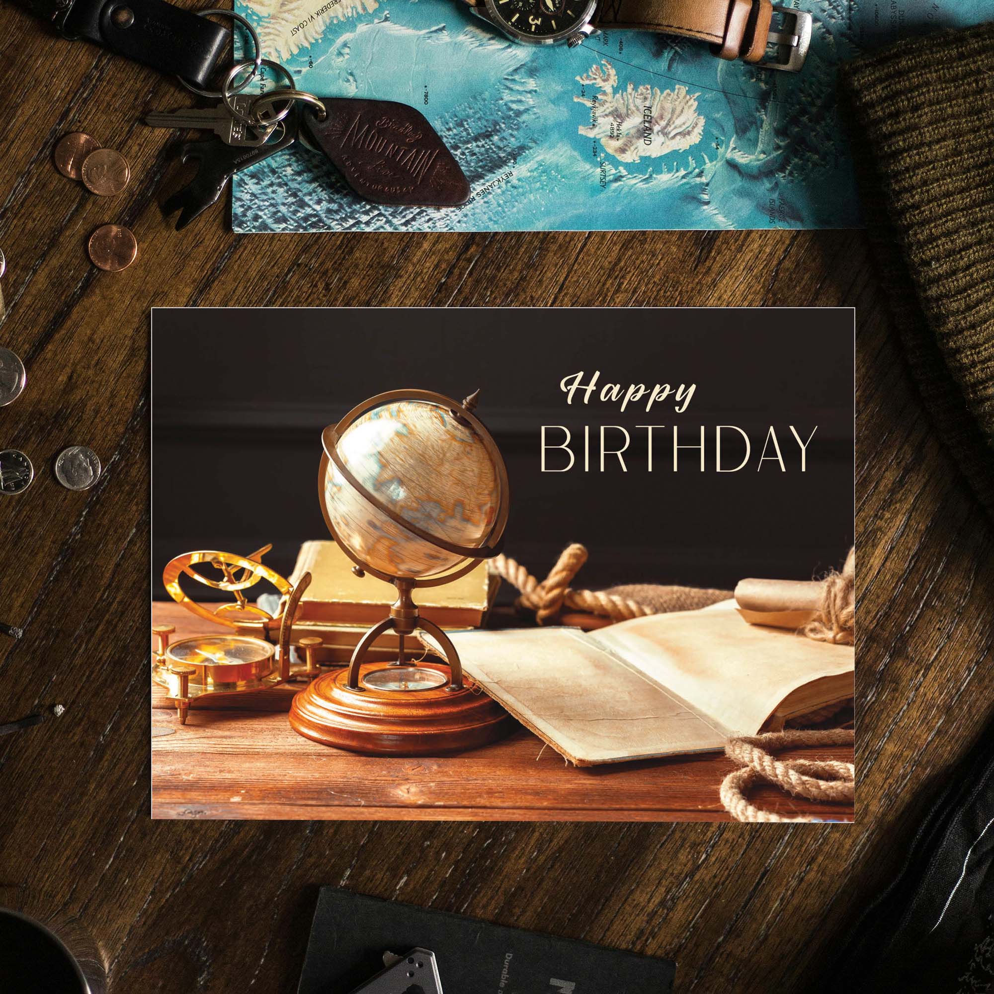 Vintage-style 'Happy Birthday' card with a globe and books on a wooden surface.