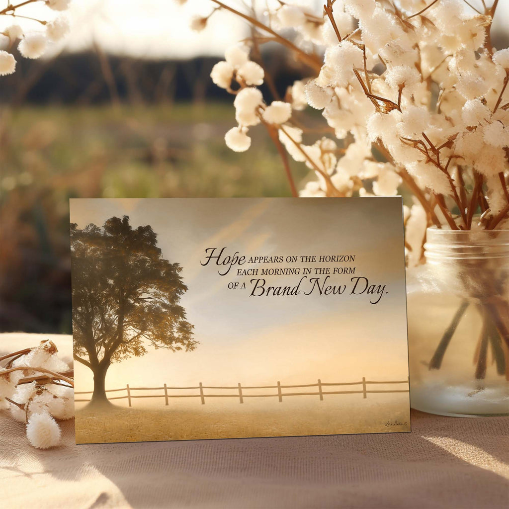 Motivational card with tree and fence illustration and text, placed on a surface with cotton plants.