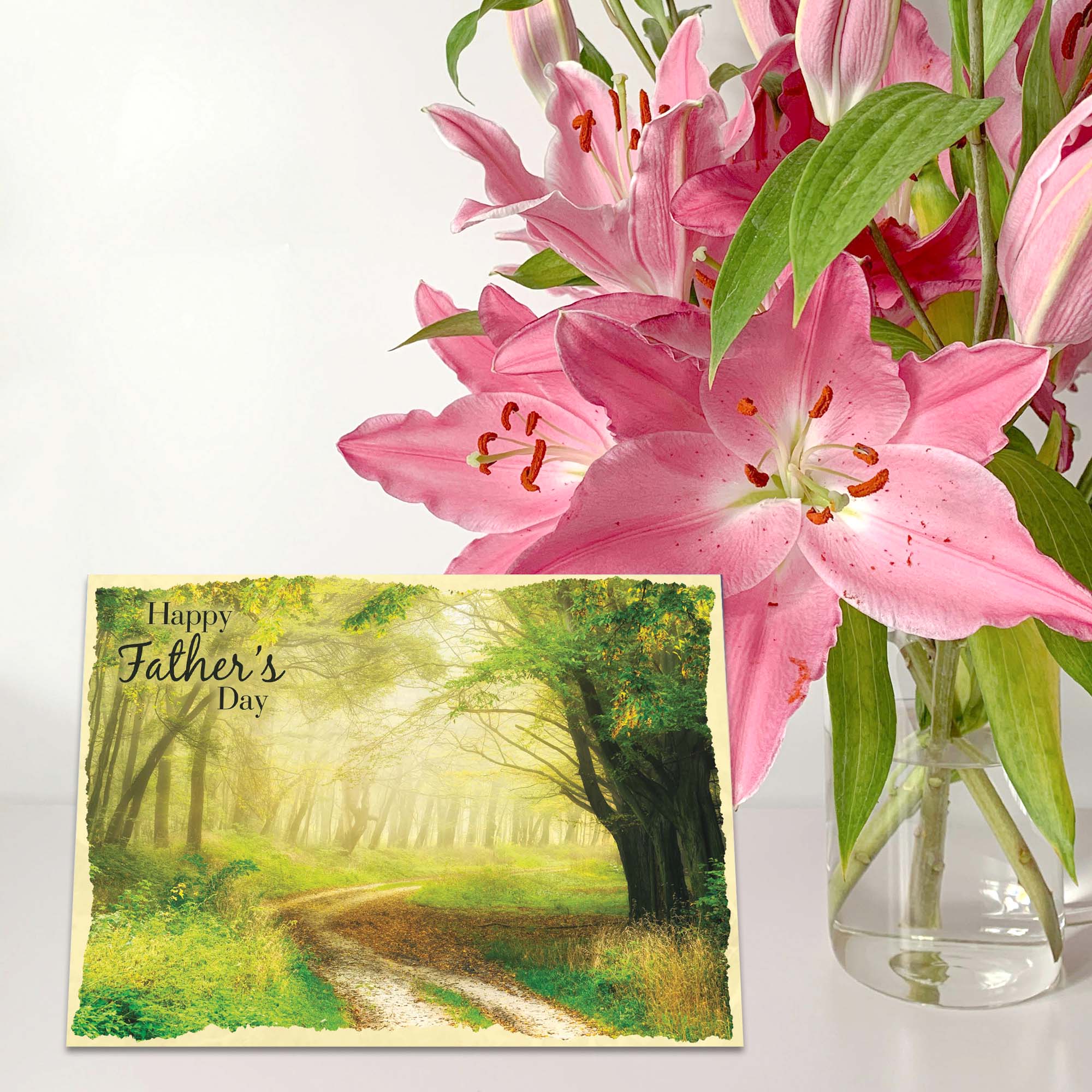 Bouquet of pink lilies with a Father's Day card featuring a forest scene.