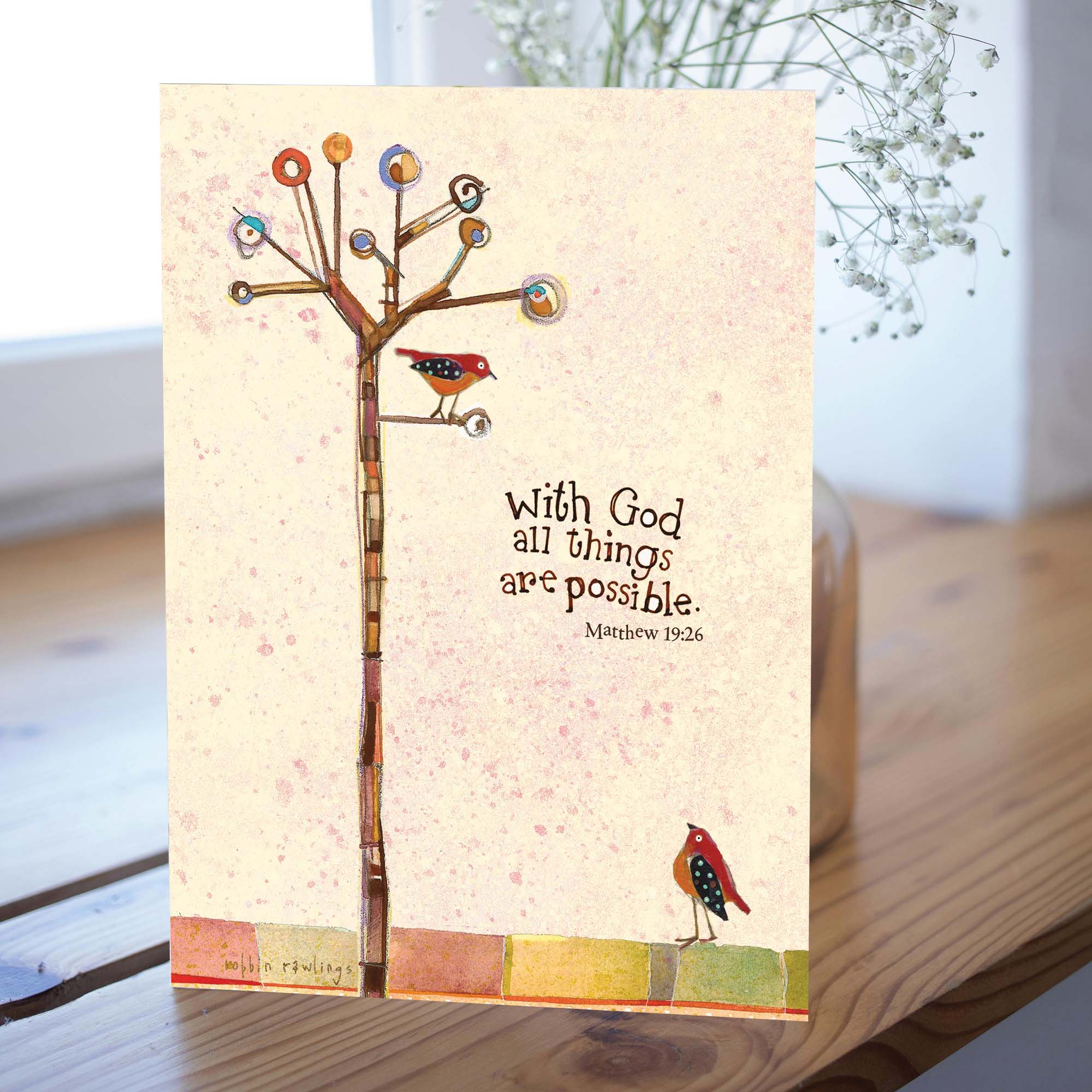 Card with tree design, birds, and motivational quote on a wooden surface.
