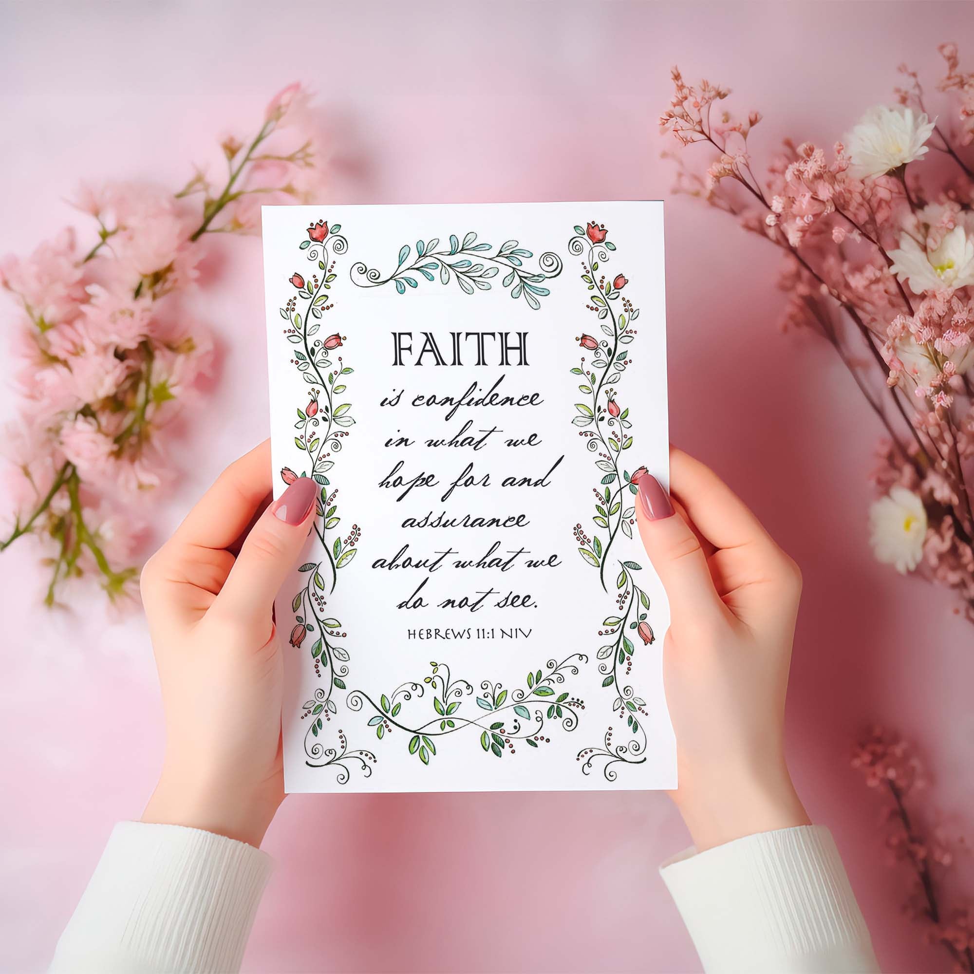 Hands holding a card with floral design and text on a pink floral background