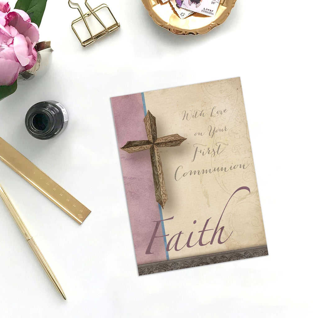 Greeting card with cross design and 'Faith' text on a white surface with stationery items.