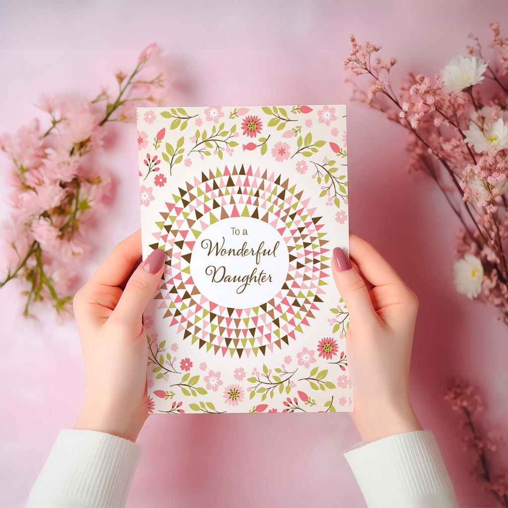 Card with 'To a Wonderful Daughter' text held by hands against a pink floral background