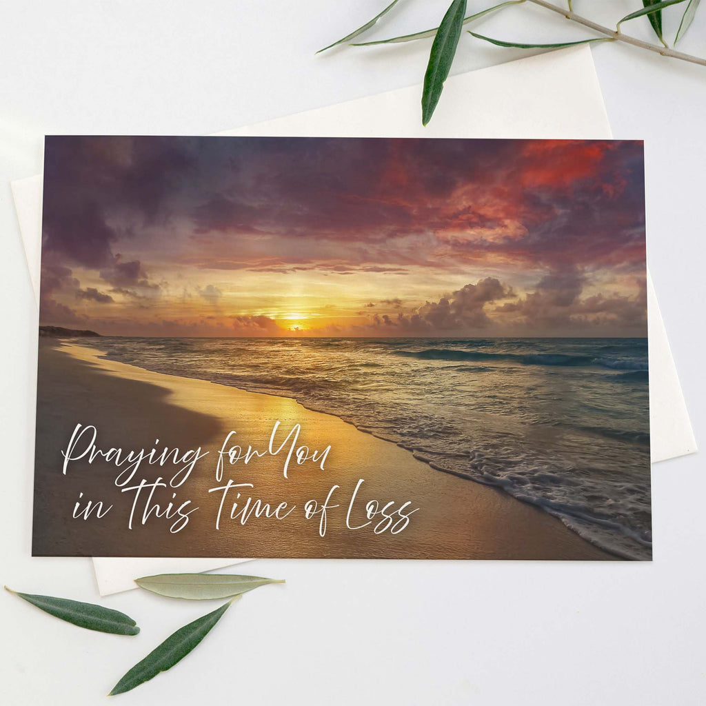 Greeting card with sunset beach scene and text 'Praying for you in this time of loss'.