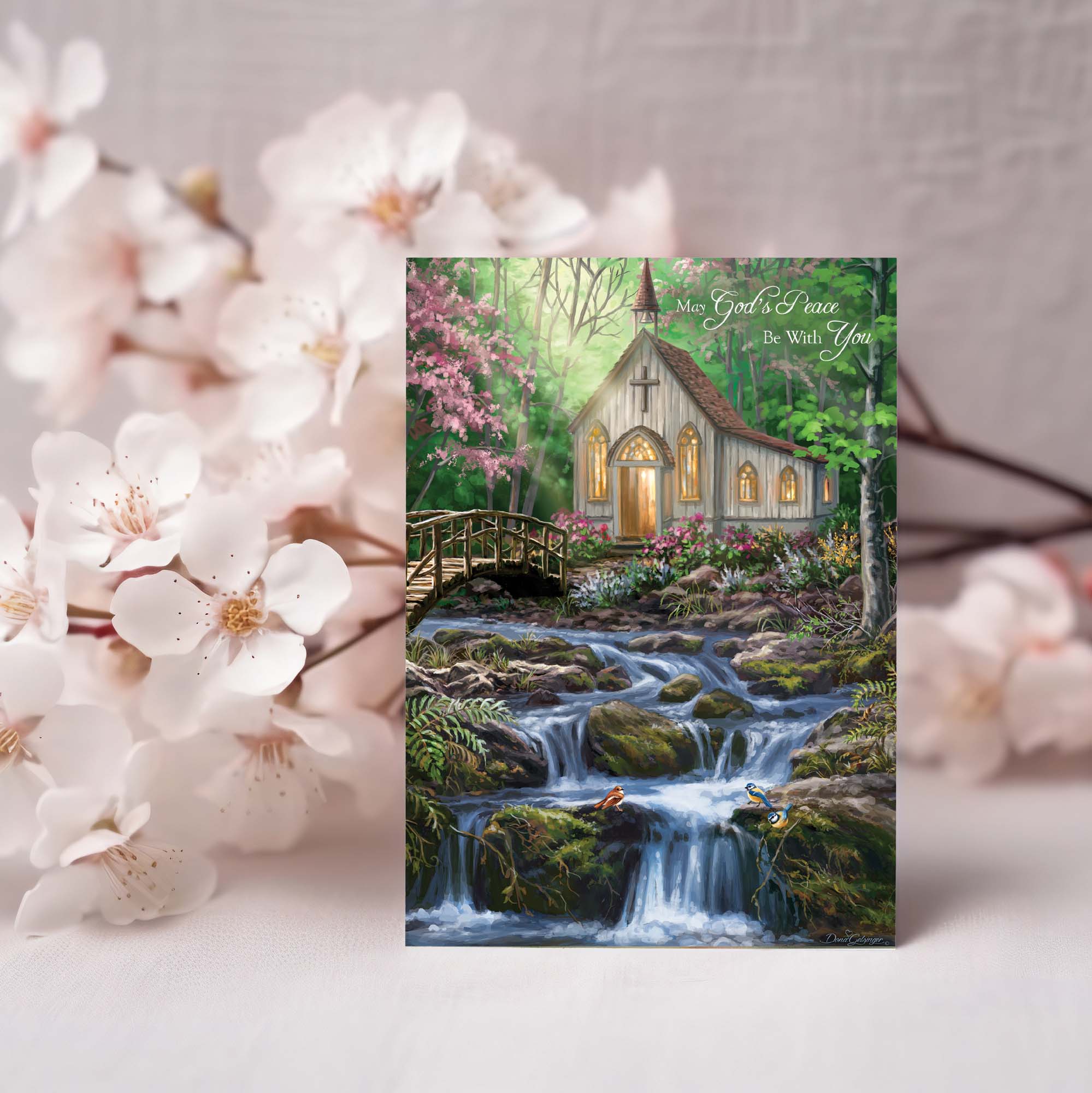 Greeting card with a scenic design of a church by a waterfall, surrounded by cherry blossoms.