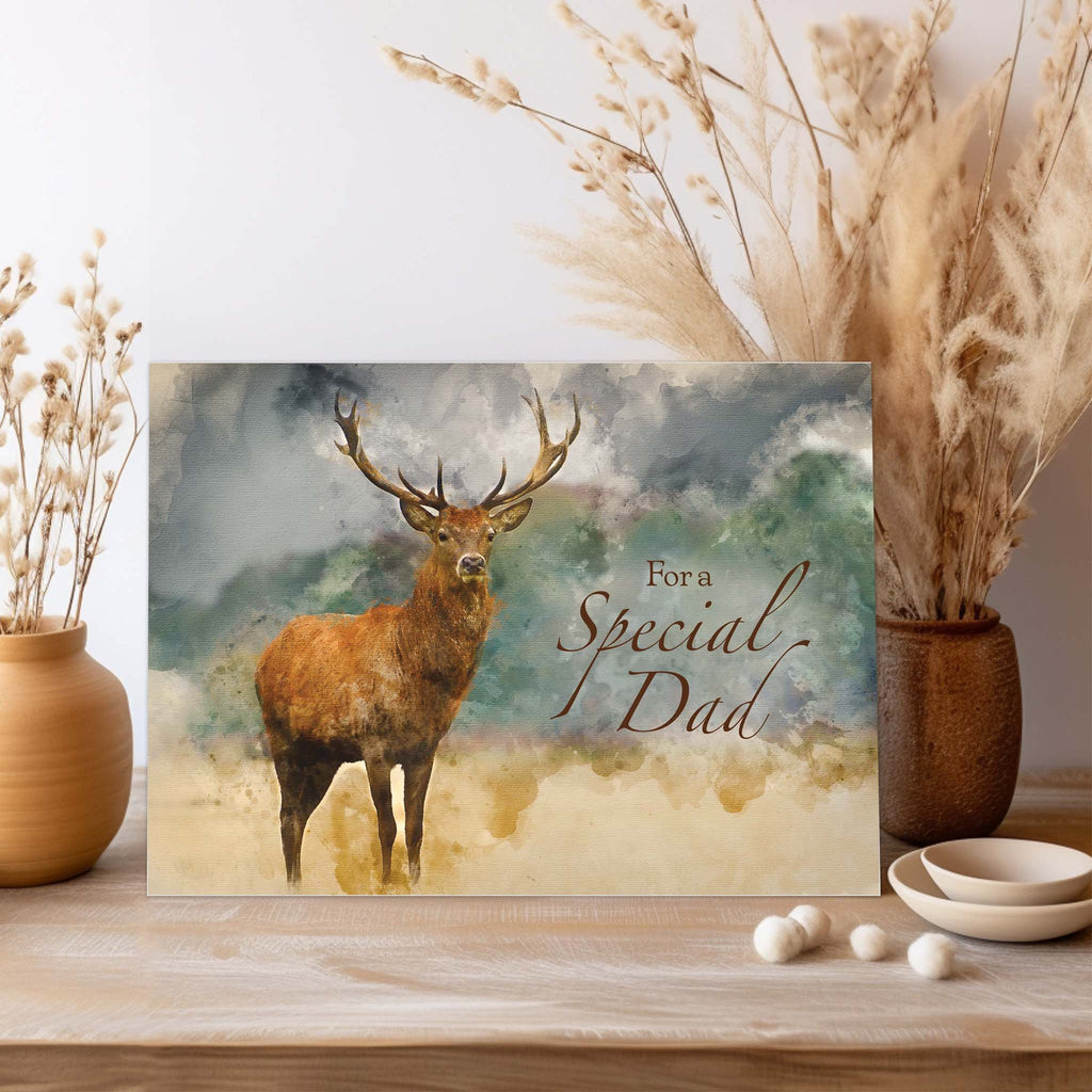 Greeting card with a deer illustration and 'For a Special Dad' text, placed on a wooden surface with decorative elements.