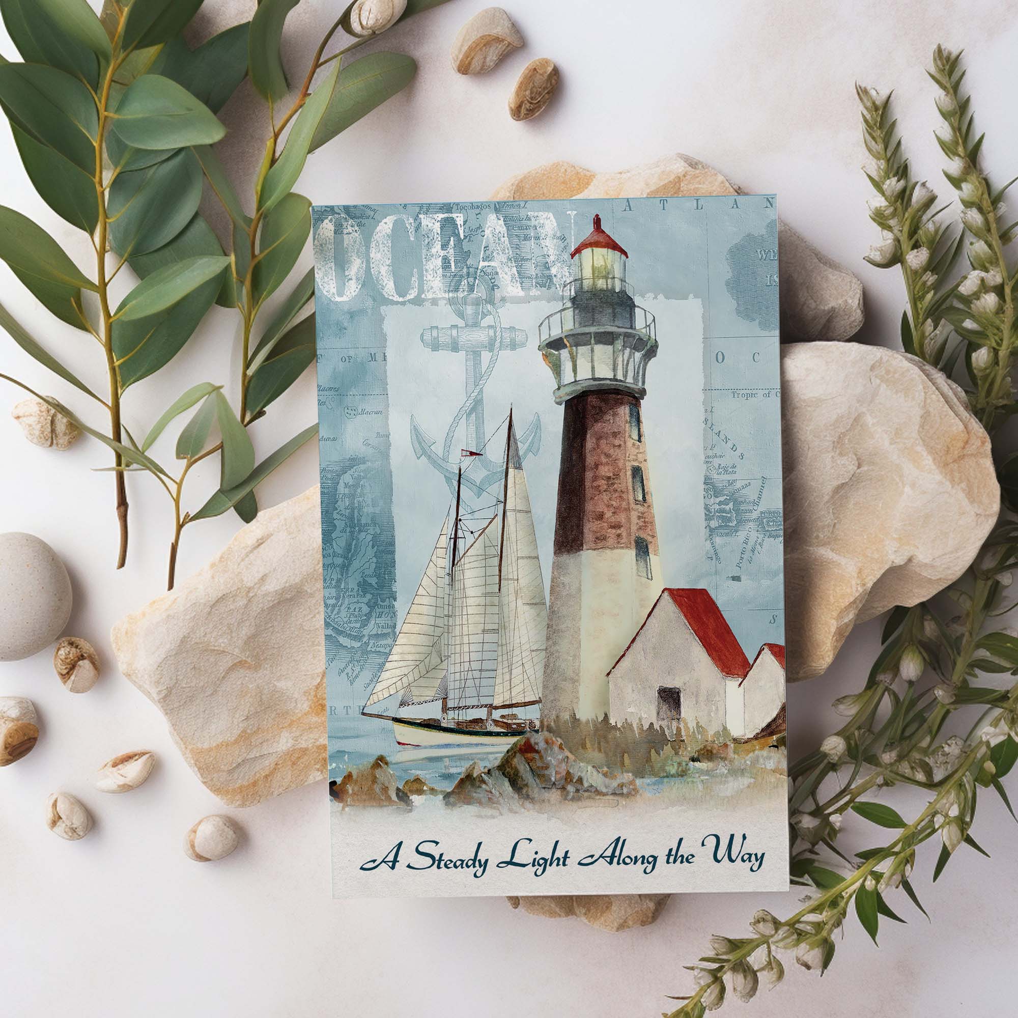 Postcard with a lighthouse and sailboat design, surrounded by stones and greenery.
