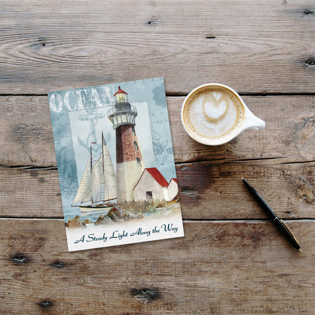 Lighthouse painting on a wooden surface with a cup of coffee and pen.