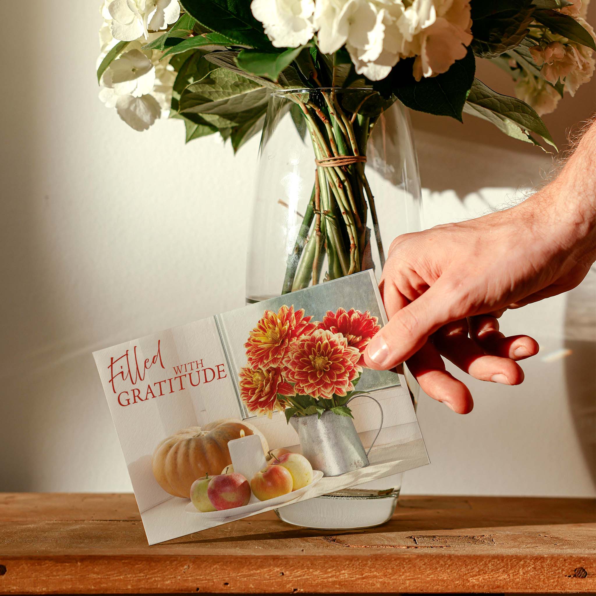 Holding Christian Thanksgiving Card on table with white flowers 