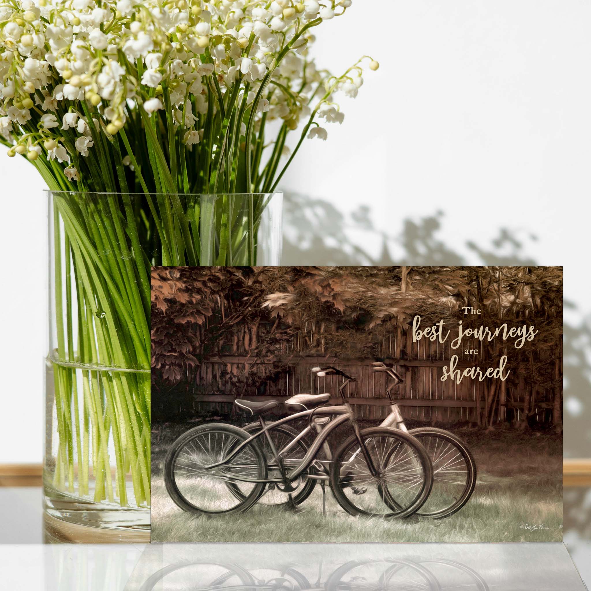 Card with bicycles on table with flowers. 